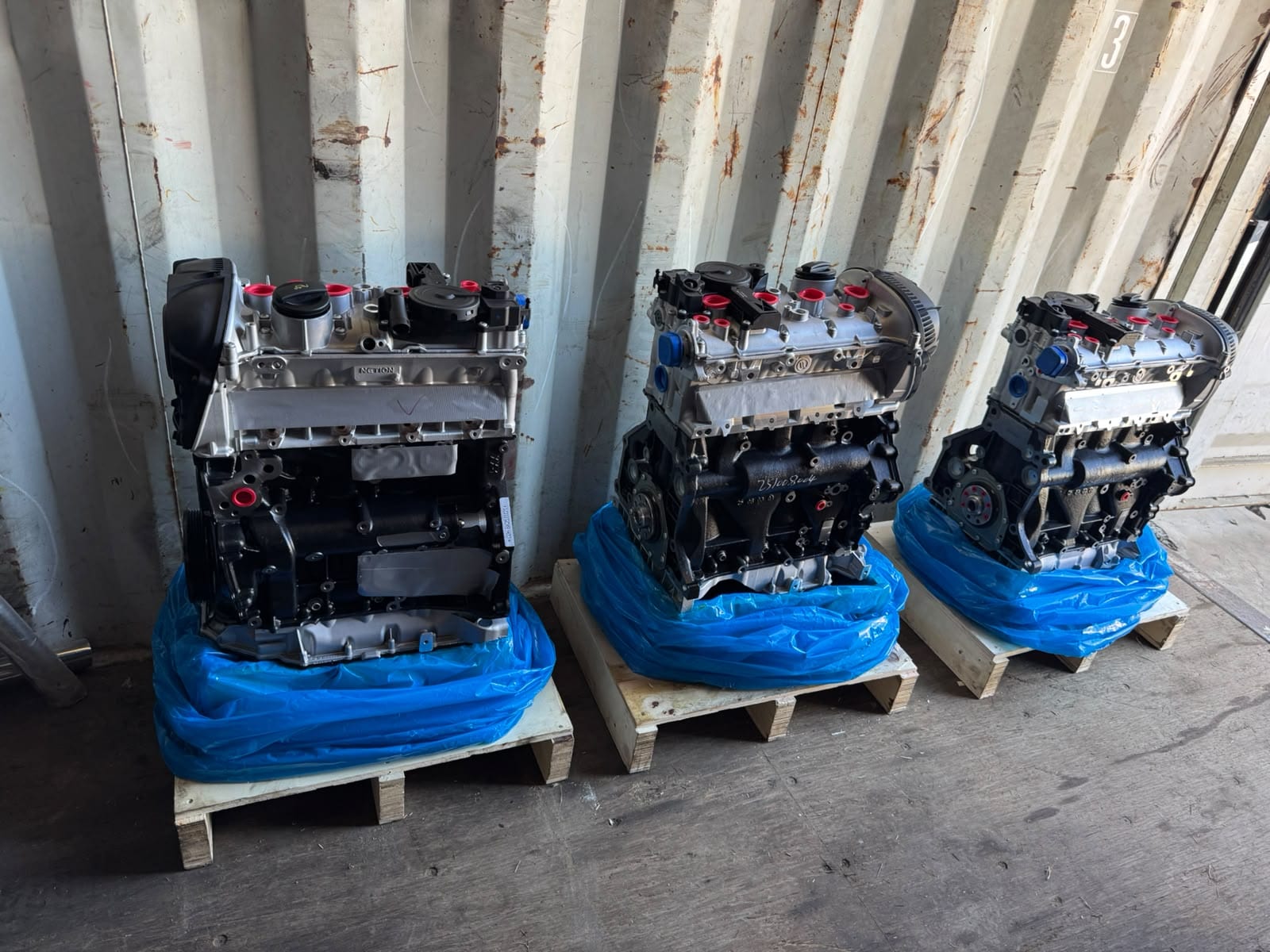 Tres motores 1.8 TFSI nuevos sobre sus pallets, dentro de un contenedor